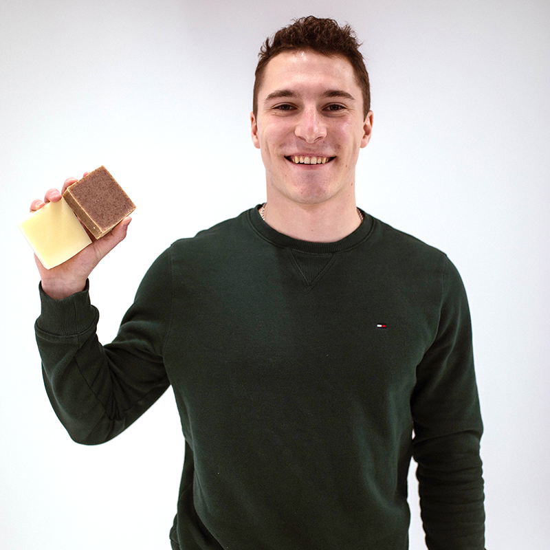 Male college student holding up a product he designed