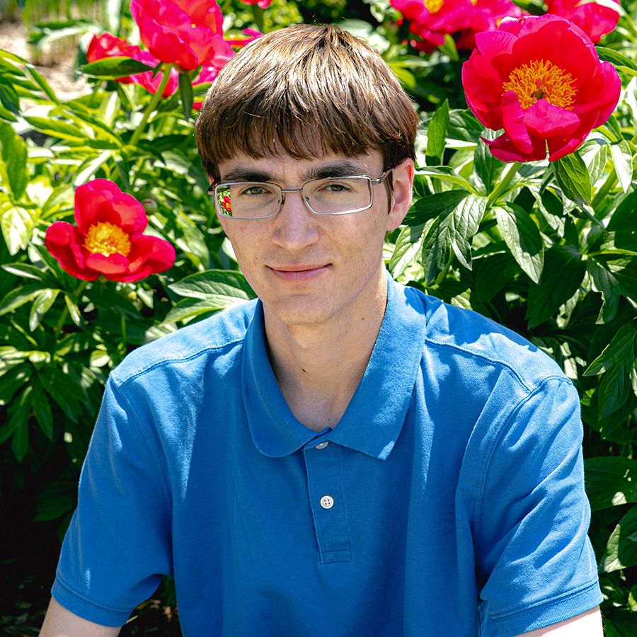 Daniel Howell sitting in front of bright red flowers